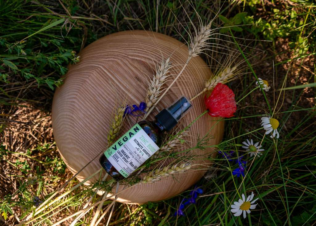 Givol Zinc Boost mist on a wooden bowl among wheat and wildflowers in a summer meadow